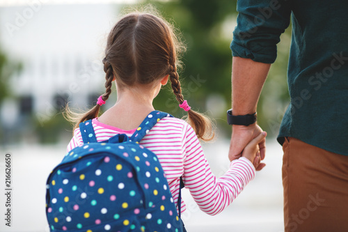 first day at school. father leads little child school girl in first grade