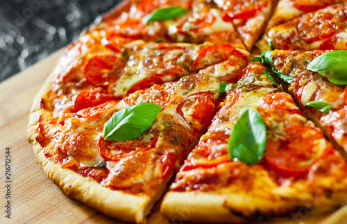 sliced Pizza with Mozzarella cheese, Tomatoes, pepper, Spices and Fresh Basil. Italian pizza. Pizza Margherita or Margarita