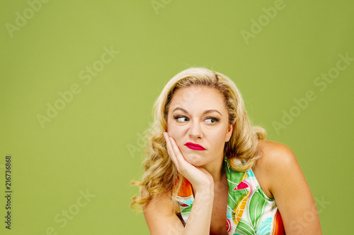 Portrait of an envious woman in bad mood looking right, isolated on green studio background