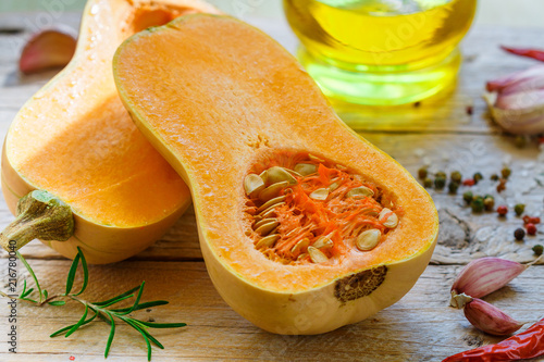 Raw organic butternut squash with ingredients for cooking on a wooden table. Selective focus