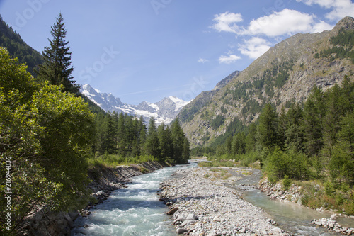 mountain stream in italian national park gran paradiso with snow capped mountains in the background