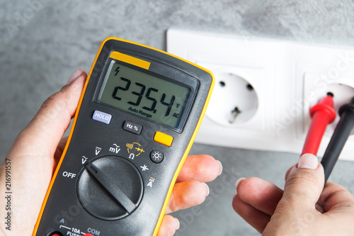 Woman checking voltage in power socket