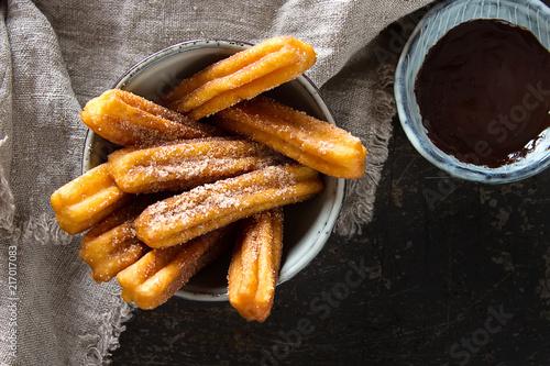 Traditional Mexican dessert churros with chocolate sauce. Dark background