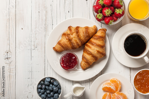 Breakfast with croissants, coffee, jams and berries