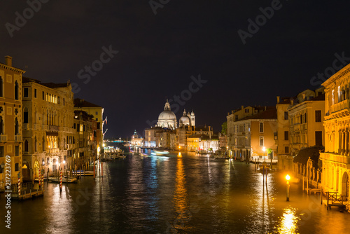 Night view of grand canal in Venice surrounded by Venetian Gothic architectures and Basilica di Santa Maria della Salute is the landmark.