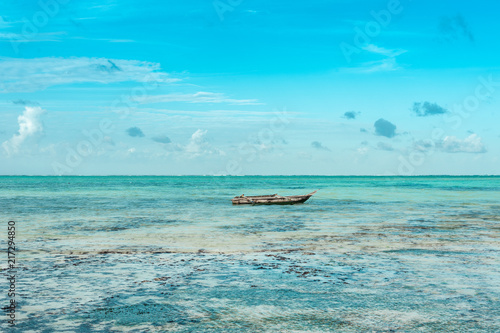 Fisherman's boat swinging on turquoise waves in the Indian ocean near the shore of the island of Zanzibar