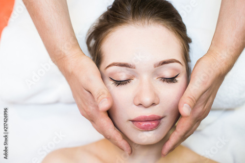 beautiful girl enjoys face massage in spa salon. Procedures for beauty and rejuvenation. Thai massage
