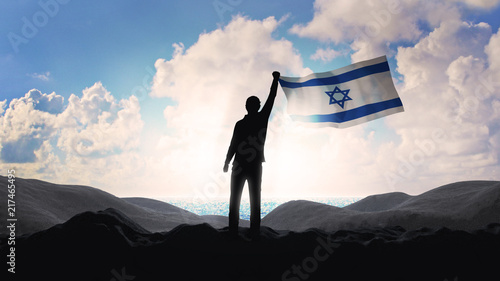 Lonely patriot Jewish man standing and looking at the sunrise on coastline of the Mediterranean Sea with the flag of Israel. Newcomer life and immigration to Israel concept. 3D render.