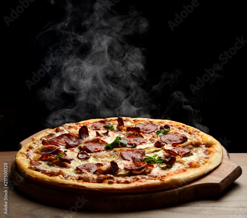 Hot big pepperoni pizza tasty pizza composition with melting cheese bacon tomatoes ham paprika steam smoke
