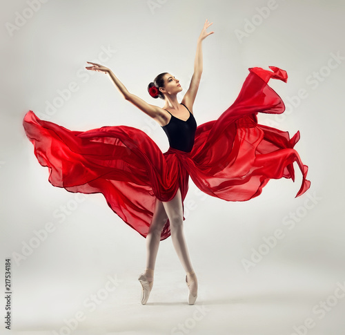 Balerina. Młoda zgrabna tancerka baletowa, ubrana w profesjonalny strój, buty i czerwoną nieważką spódnicę, demonstruje umiejętności taneczne. Piękno klasycznego tańca baletowego.