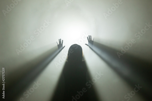Licht am Ende des Tunnels - Silhoutte einer weiblichen Person im Gegellicht mit Nebel, die die Hände hebt