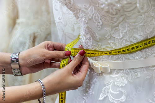 Female hands with measuring tape and wedding dress