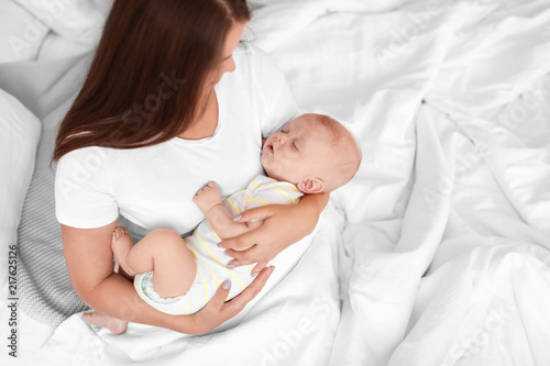 Mother with her sleeping baby in bed at home