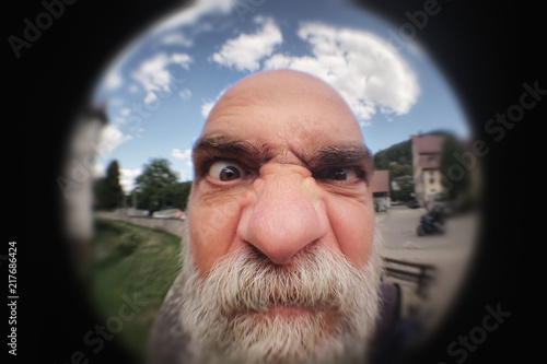 an angry man looking to a peephole door