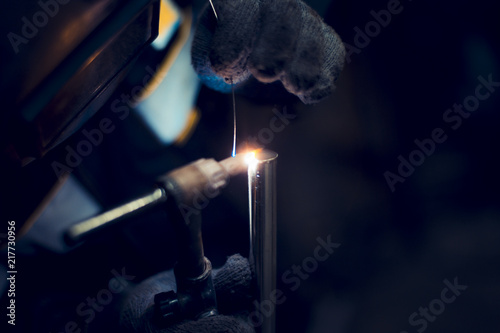 Argon-arc welding welder at the workplace welds the part