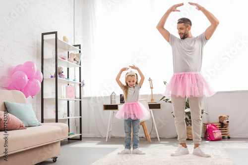 father and daughter in pink tutu skirts dancing like ballerinas