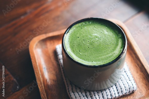 A cup of hot matcha latte on wooden floor