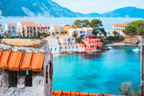 Tile chimney in front of Assos village. Beautiful view to vivid colorful houses near blue turquoise colored transparent bay lagoon. Kefalonia, Greece