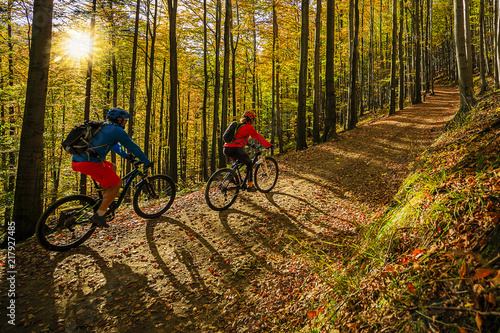 Kolarstwo, para rowerzystów górskich na szlaku rowerowym w lesie jesienią. Kolarstwo górskie w jesień krajobraz lasu. Mężczyzna i kobieta na rowerze MTB płyną pod górę szlaku.