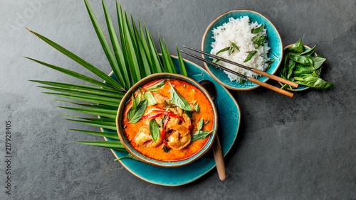 THAI SHRIMPS RED CURRY. Thailand Thai tradition red curry soup with shrimps prawns and coconut milk. Panaeng Curry in blue plate on gray background