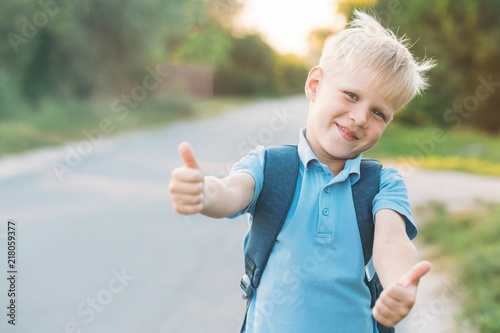 Cheerful boy staying on the sidelines and gives a thumbs-up. Schoolboy likes education.