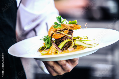 Modern food stylist decorating meal for presentation in restaurant. Closeup of food stylish. Restaurant serving. Close-up on the hand of a waiter carrying food