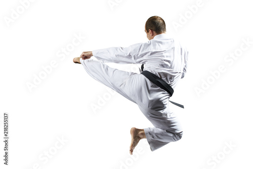 In karategi, an athlete beats a kick in jump against a white background isolated