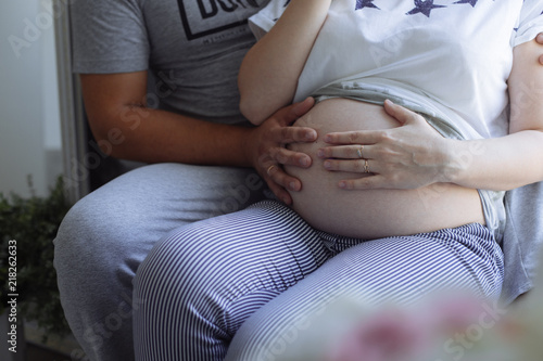 the man strokes the belly of his pregnant wife. two hands on the tummy of the pregnant woman. a couple in the pay of a child. 