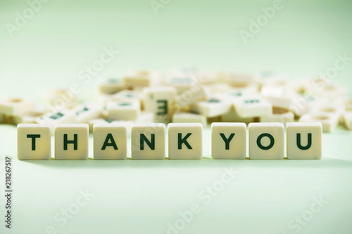 The word THANK YOU on pastel background, spelt with scrabble tiles