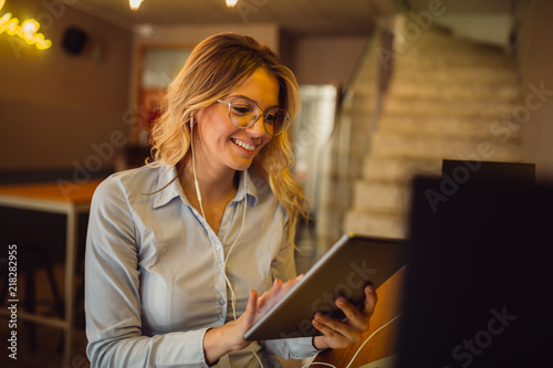 Portrait of beautiful blonde woman with earphones having online call on tablet computer