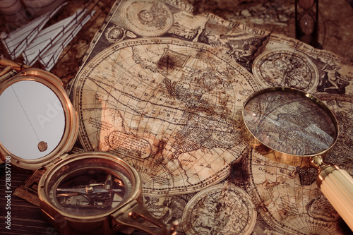 Old vintage maps and marine equipment like compass, magnifier or hourglass and ship. Columbus Day concept.