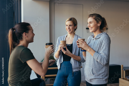 Fitness women drinking coffee after workout in a gym