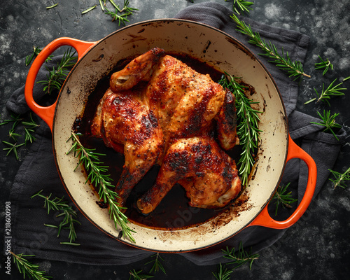 Grilled fried roast Chicken Tabaka in frying pan with rosemary