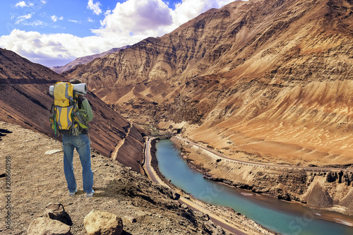 Tourist male backpacker enjoy an aerial view of Zanskar valley Ladakh with confluence point of Zanskar with river Indus.