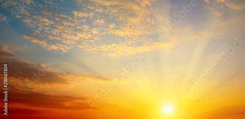 Cloudy sky and bright sun rise over the horizon. Wide photo .