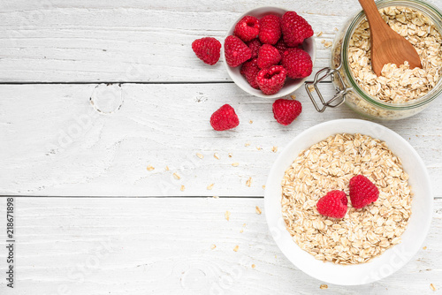 homemade oat muesli with fresh raspberries and milk on white wooden background. healthy breakfast. top view