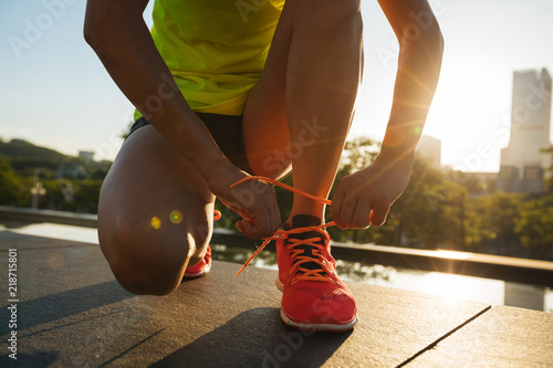  Fitness woman runner tying shoelace before running