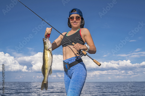 Happy fisher woman with zander fish trophy at the boat