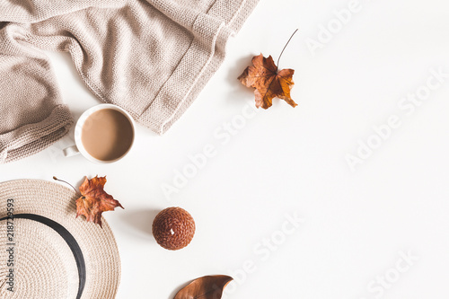 Autumn composition. Cup of coffee, hat, dried autumn leaves, beige sweater on white background. Flat lay, top view, copy space