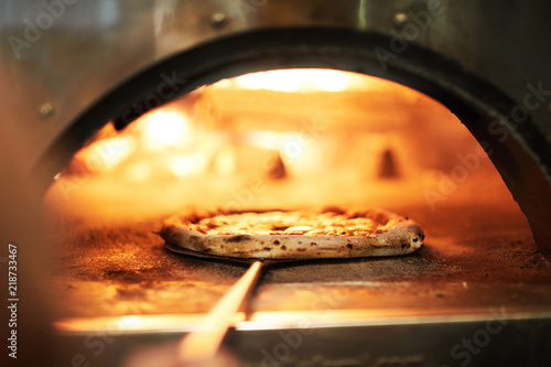 Special tray with handle with raw pizza inside oven for roasting on fire