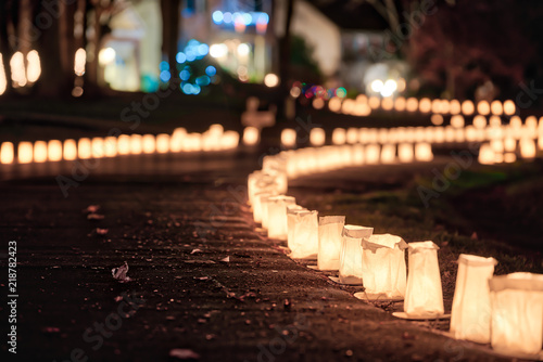 Christmas Eve candle lights, lanterns in paper bags at night along road, street, path illuminated by houses in residential neighborhood in Virginia