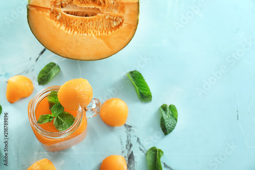 Mason jar with delicious smoothie and melon on table