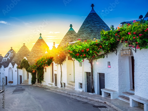 Traditional Trulli houses in Alberobello village, illuminated at sunrise in Bari region of Italy.