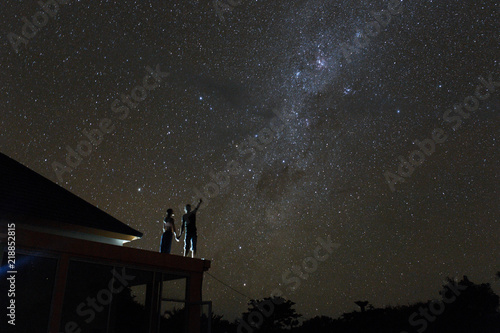 Couple on rooftop watching mliky way and catching stars in the night sky on Bali island