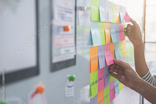 Web designer brainstorming for a strategy plan. Colorful sticky notes with things to do on office board. User experience (UX) concept.