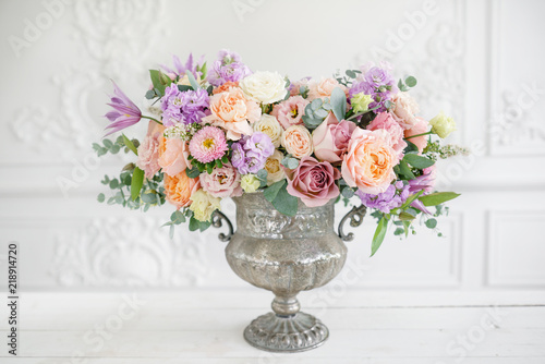 Gorgeous bouquet of different flowers. floral arrangement in vintage metal vase. table setting. lilac and peach color