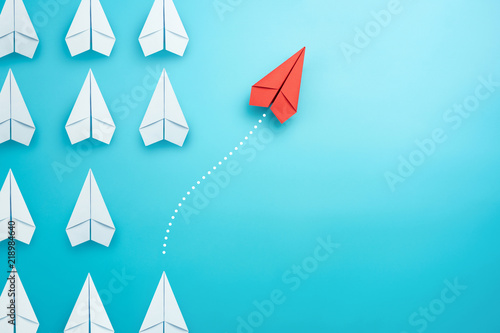 Group of white paper plane in one direction and one red paper plane pointing in different way on blue background. Business for innovative solution concept.