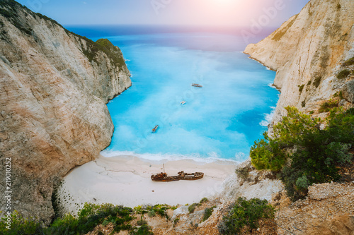 Breathtaking view of Shipwreck middle of sandy Navagio beach surrounded by azure deep turquoise sea saltwater and huge white cliff limestone rocks. Zakynthos island, Greece