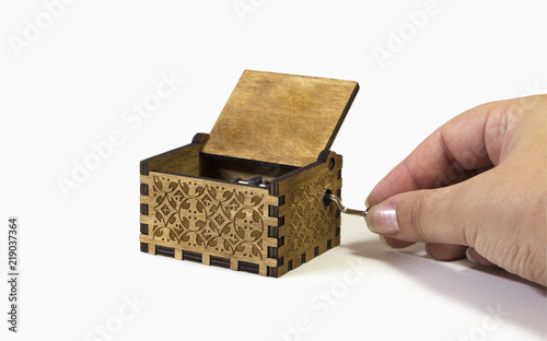 Woman's hand playing a music box. Macro of the music box in white background with intricate patterns and texture.