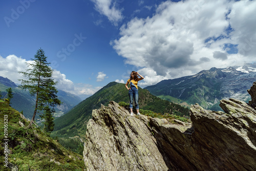 Young teenage girl posing on big stone in Alps